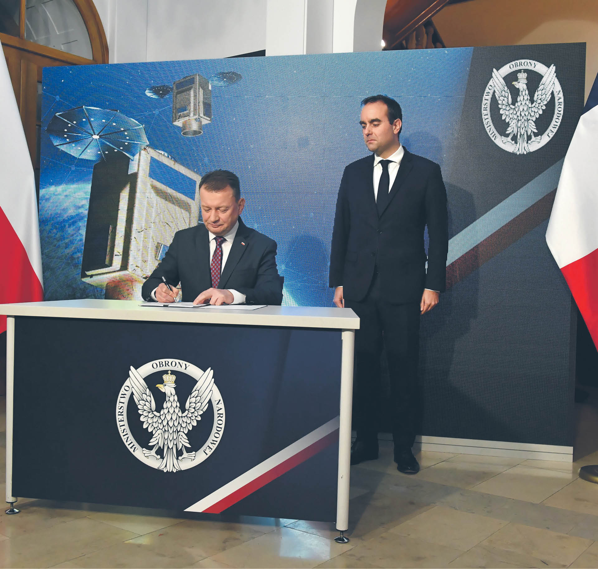 Szef MON Mariusz Błaszczak oraz jego francuski odpowiednik Sebastien Lecornu podpisują umowę na dostawę satelitów obserwacyjnych