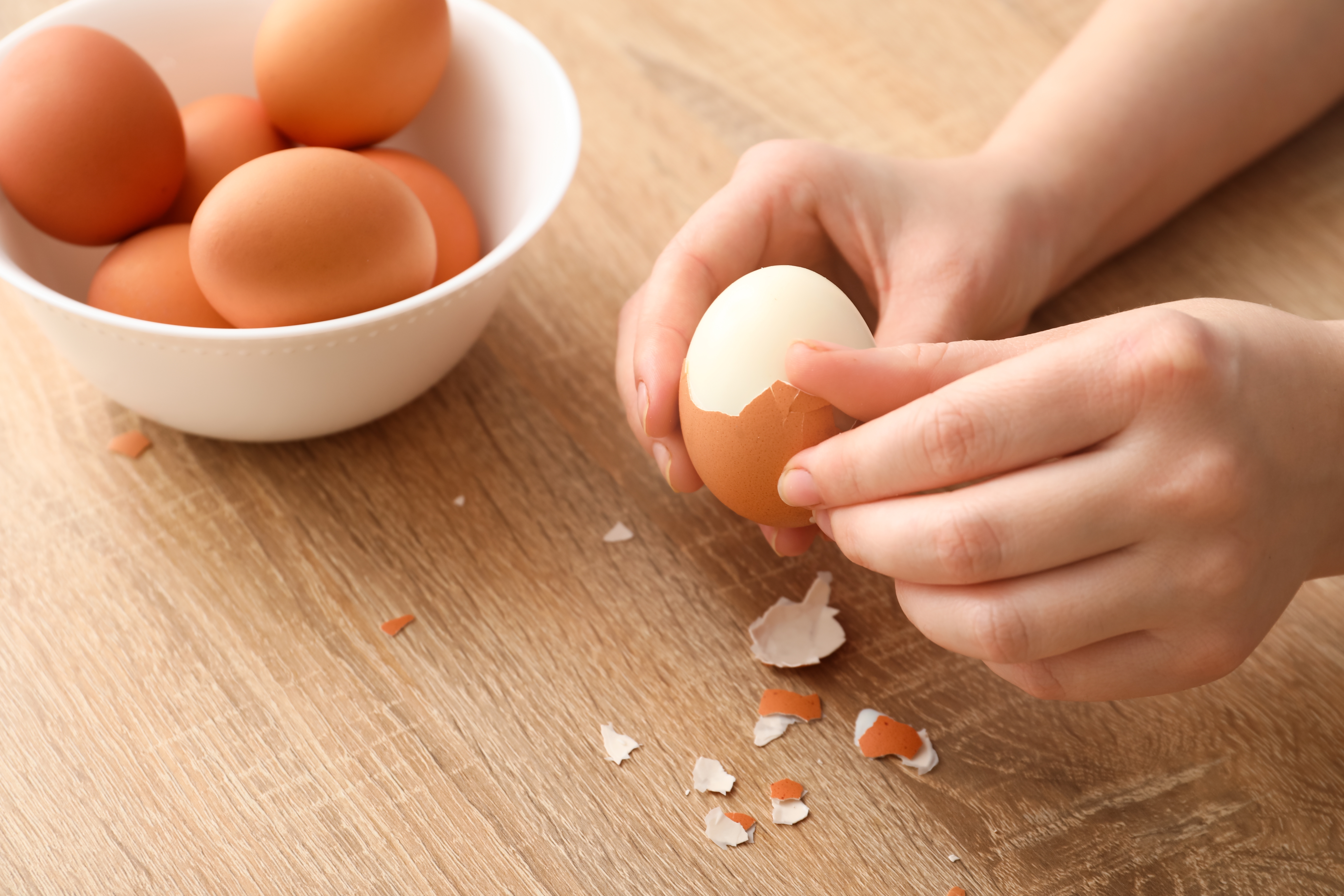 Jajko jajka Woman,Peeling,Boiled,Egg,On,Wooden,Table,,Closeup