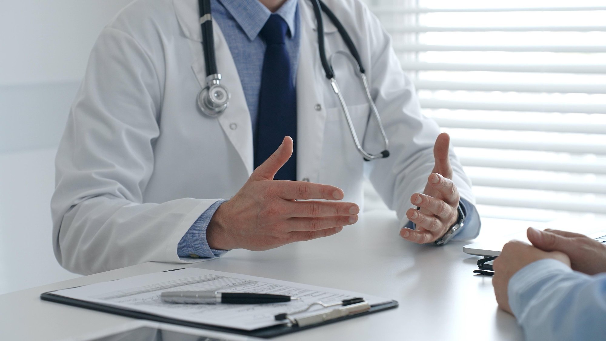 Male,Doctor,Explaining,Diagnosis,,Gesturing,With,Hand,To,Patient,During